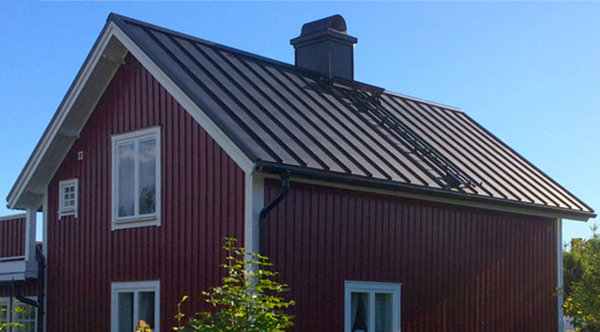 Rött hus med svart listtäckt tak där potentiell plats för framtida solpaneler syns.