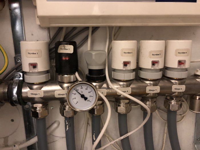 Värmesystem med sex styrdon och slingleledningar, med en manometer i förgrunden och fokus på styrdon 6.