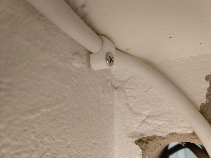 Elkabel dragen oprofessionellt i hörnet av ett tak och en vägg, inte helt dikt an, med stora klamrar.
