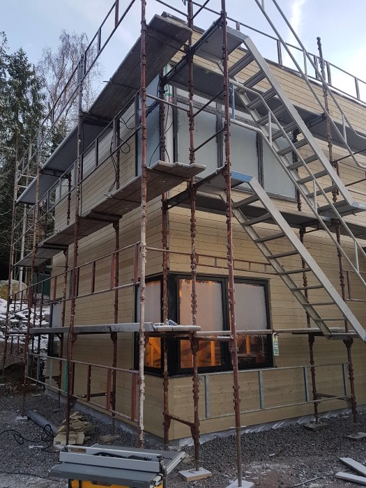 Hus under renovering med ny panel och byggnadsställningar runtomkring.