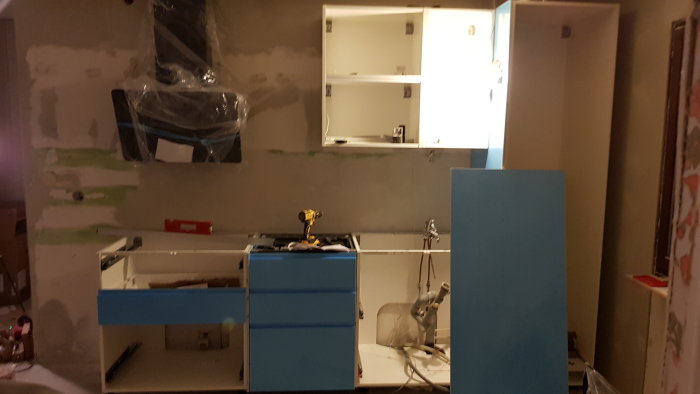 Pågående montering av Ikea kök med omonterade skåp och verktyg synliga.
