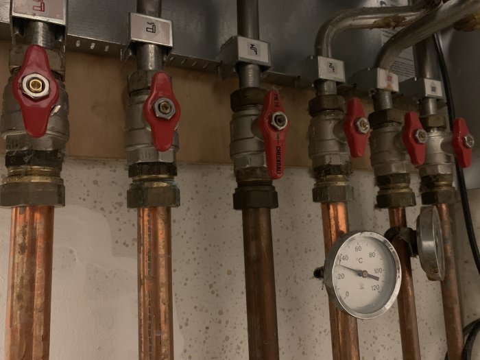 Radiatorrör och ventiler med etiketter och en termometer som visar låg temperatur.