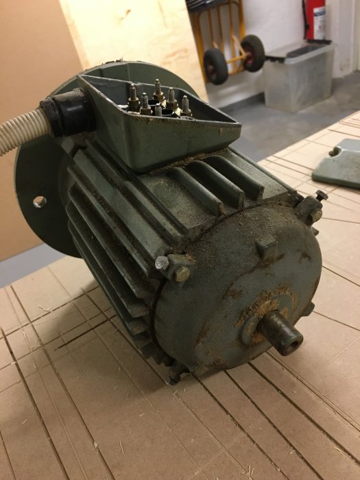 Gammal elektromotor demonterad och redo för underhåll och målning på verkstadsgolv.