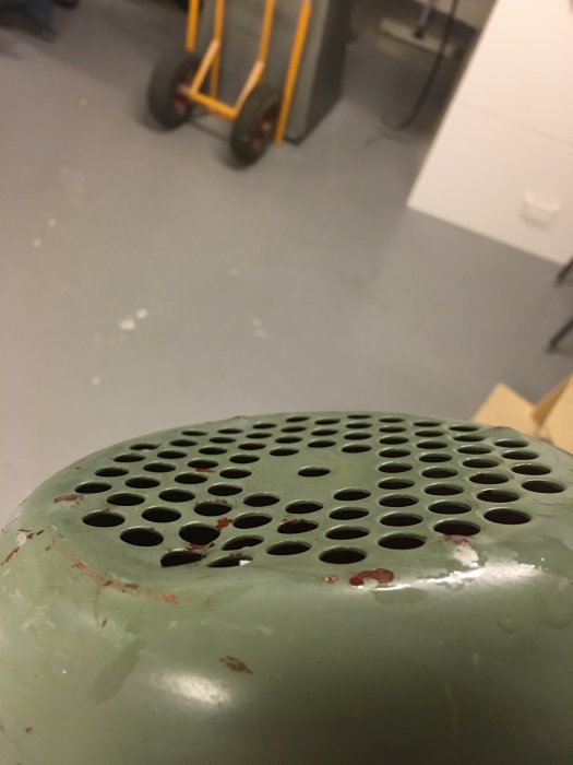 Närbild på rostig och sliten del av ett fordon med hålplåt, före renovering och målning.