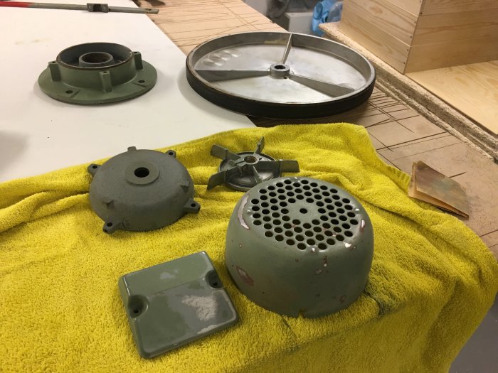Demonterade delar av ett fordon inklusive broms och fjäder ligger på en gul handduk för rengöring och underhåll.