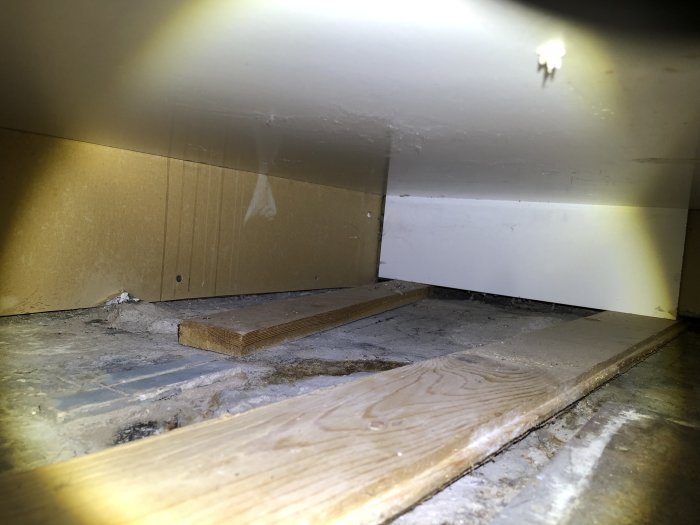 Bild av gap mellan golvet och golvreglar under köksskåp, tecken på drag och fukt.