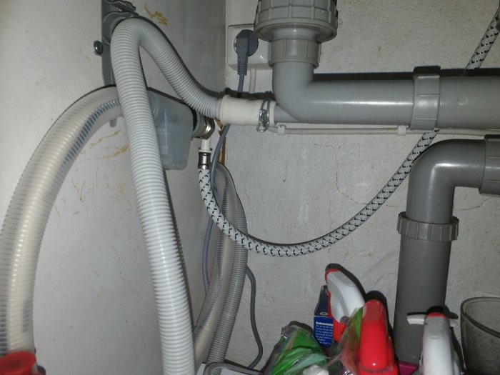 Rörkopplingar under diskbänk med slangar, ballofix och mellankoppling i en rörig installation.