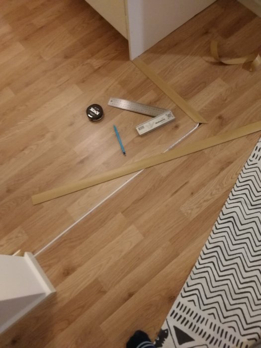 Vattenledning för ismaskin dragen längs golv med tejp, linjal och penna synliga.