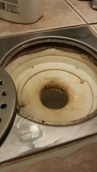 Golvavlopp med felaktigt skuret tätskikt runt, synliga rörkanter och smuts, behöver temporär tätning.