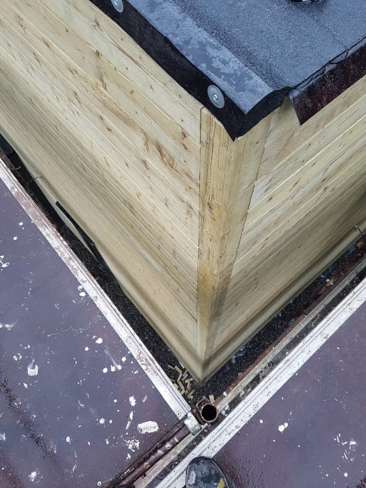 Hörnet av ett nytt trähus med monterade regnrännor från Lindab, stupröret placerat i mitten av väggen.