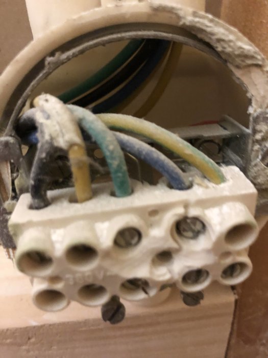 Elektrisk dosa i vägg med exponerade trådar och anslutningsklemmar under installation.