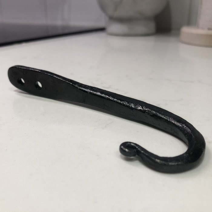 Handsmidd svart väggkrok på en vit bänkskiva.