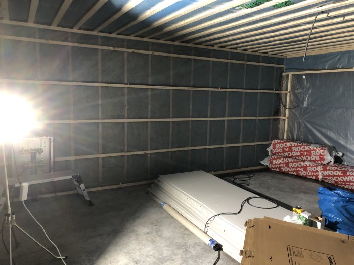 Garage under renovering med uppreglade väggar och byggmaterial på golvet.