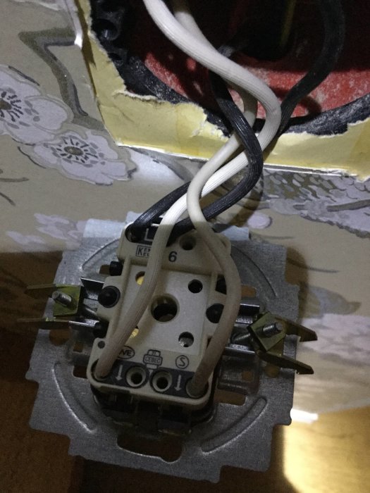 Elektrisk anslutning med öppen väggdosa där vita och svarta ledningar ansluter till en Elko 315 strömbrytare.