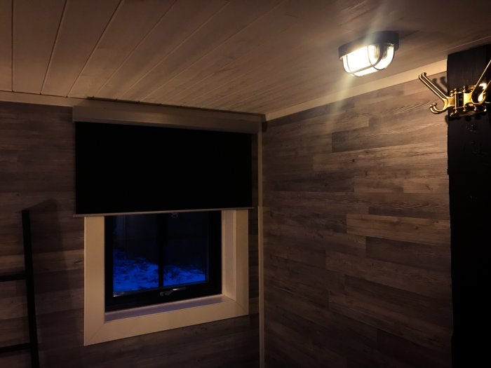 Sovrum med mörkläggningsgardin, läslampa, mobilhållare och extra hängare vid en säng.HttpSession