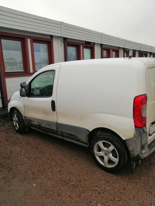 Vit Fiat Fiorino skåpbil parkerad på grus under dagtid.