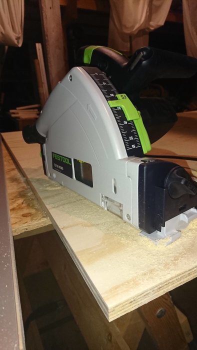 En Festool sänksåg i arbete, sågar genom plywood skapandes ett slätt spår.