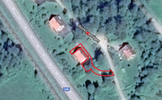 Satellitbild över en uppfart och backe markerade med röda linjer vid ett hus intill en väg.