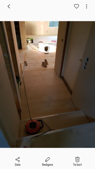 Nyinstallerad vit ekparkett i ett rum under renovering med dammsugare och arbetslampor.