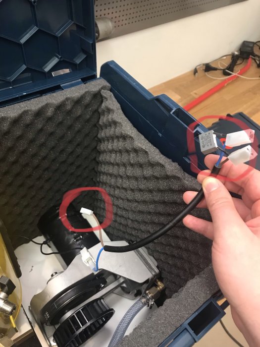 Person som håller en elkabel nära en delvis monterad bärbar kompressor i en l-boxx med skumfodring.