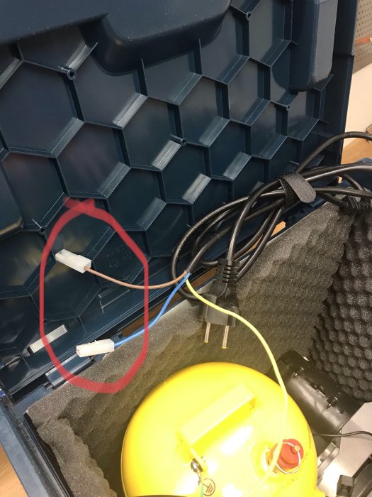 Delar av en bärbar kompressor och elektriska komponenter inuti en skyddande förvaringslåda.