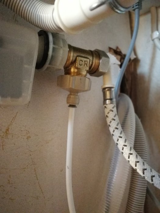 Rörkoppling med slangar och ventiler under en diskbänk, installerad med produkter från Rinkaby rör.