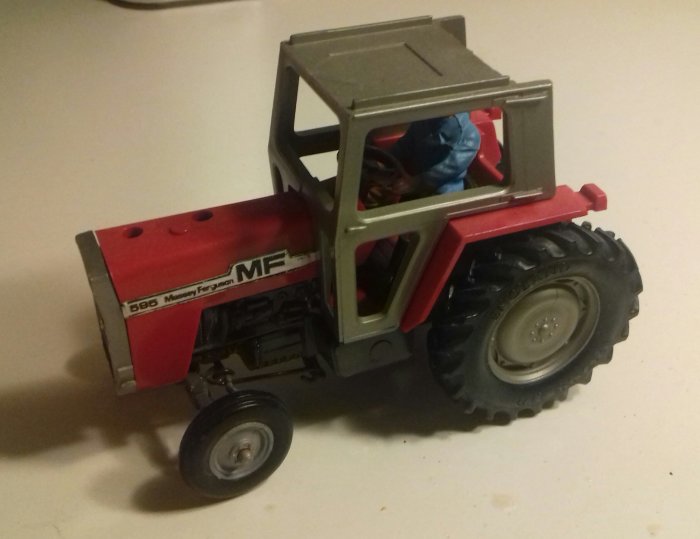 Modell av en Massey Ferguson 595a traktor med leksaksfigur i förarsätet.