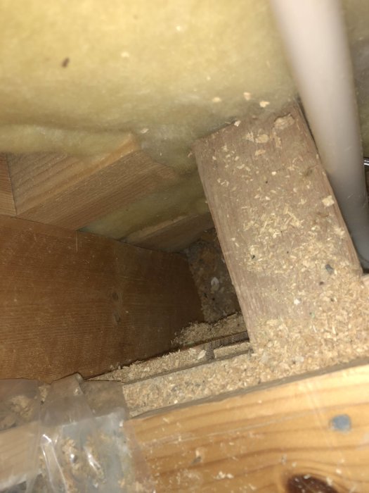 Træbjælke med spån og isolering omkring, muligvis del af husets konstruktion.