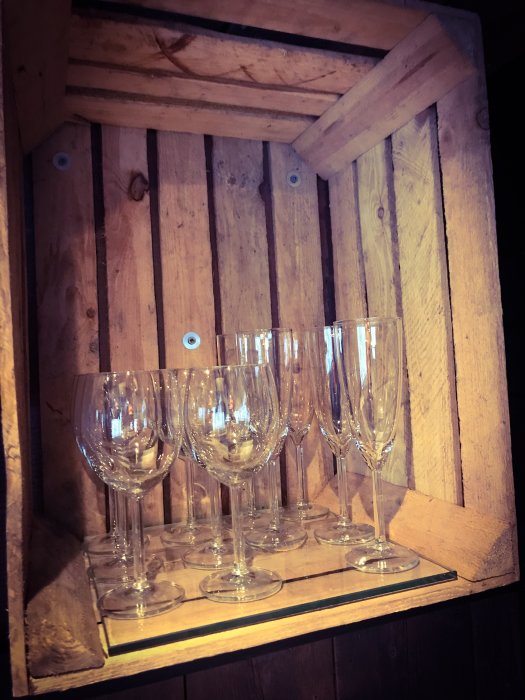 Glas vinglas och champagneglas fint ordnade i en trähylla i en nybyggd skidstuga.