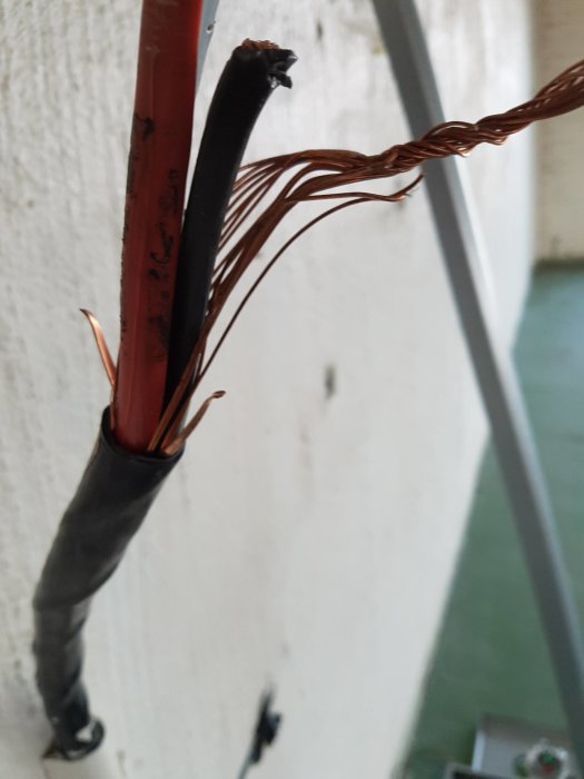 Avskalad EKKJ 16mm2 kabel med synliga kopparledare och jordtråd virad runt, mot en vit bakgrund.