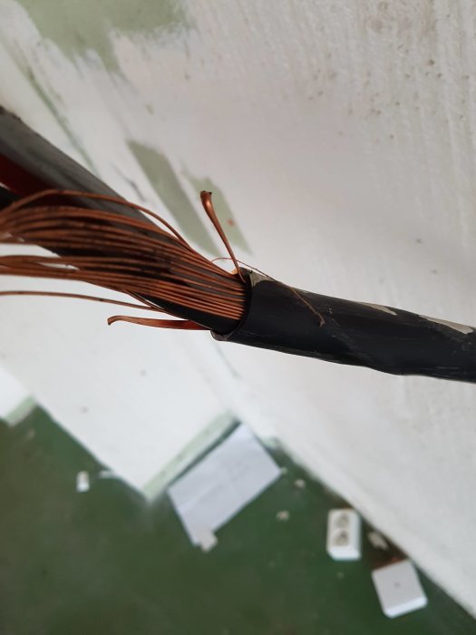 EKKJ 16mm2 kabel med jordtråd virad runt de tre fasledarna, nära en vit vägg.