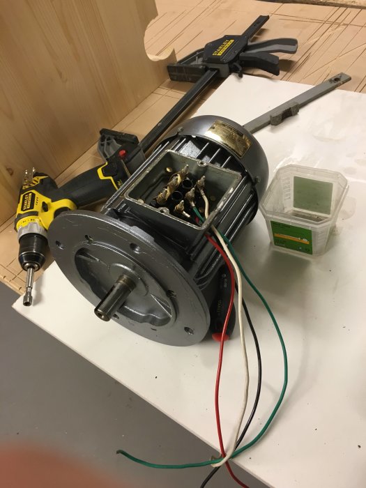 Motor med nymålad grå finish och polerade vred, verktyg och kablar på ett arbetsbord.