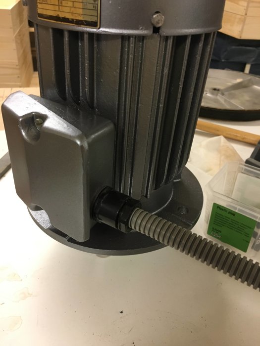 Nygråmålad motor med slipad yta och nytt grått elrör, redo för smörjning, mot bakgrund av verktyg.