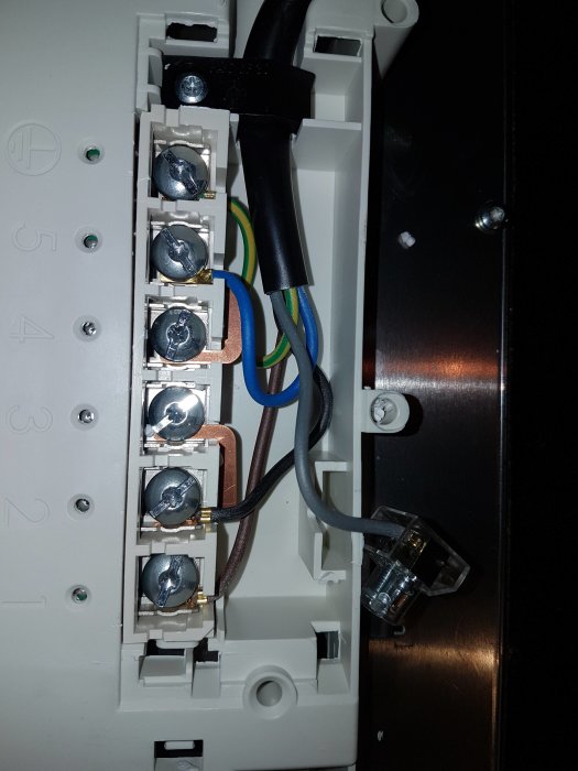 Elektrisk anslutning i häll med märkt brun, svart och blå kabel samt oanvänd grå kabel.