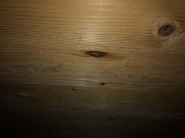 Vattenfläck på träbjälklag som tyder på en läcka i taket.