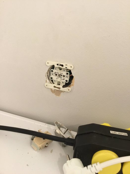Öppen eluttag utan täckplatta över torktumlare med närliggande grenuttag och sladdar.