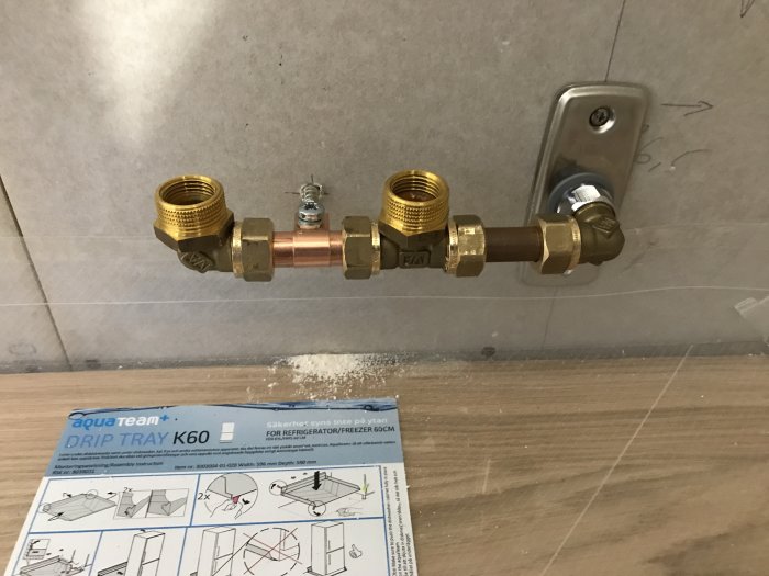 Gängad metall-bussning monterad på klämringskoppling för Vatette T-koppling på vägg.