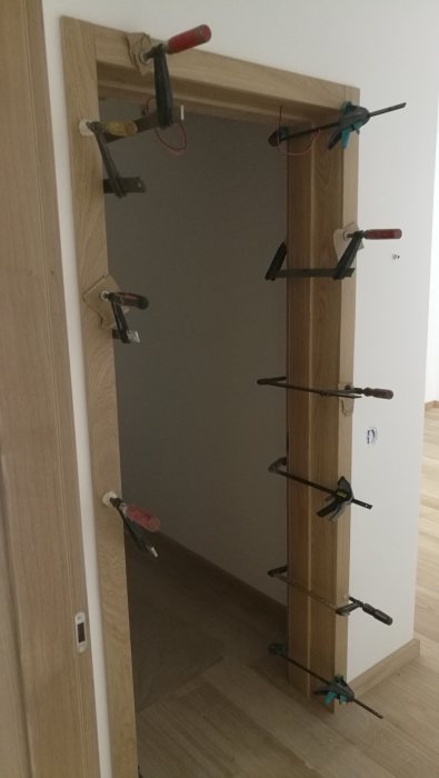 Dörrkarm under montering med klämmor som håller smygen och fodret på plats.