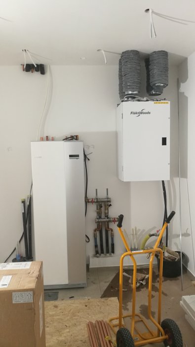 Installation av en värmepump i ett rum under konstruktion med synliga rör och kablar.
