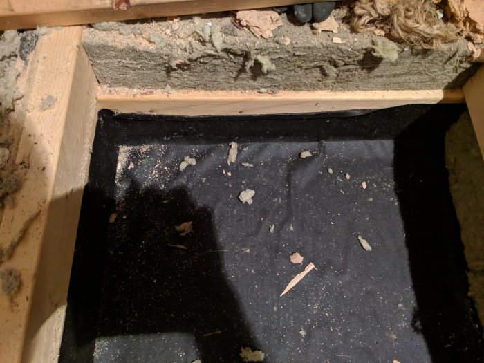 Öppet golv med synlig isolering och vindpapp, tecken på renoveringsarbete för att minska drag.