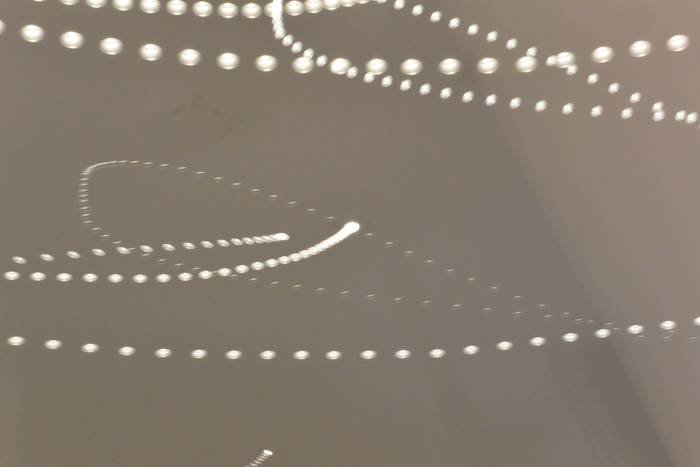 Ljuspunkter av dimmbara LEDspots på ett tak som bildar en spårliknande effekt med lång exponeringstid.