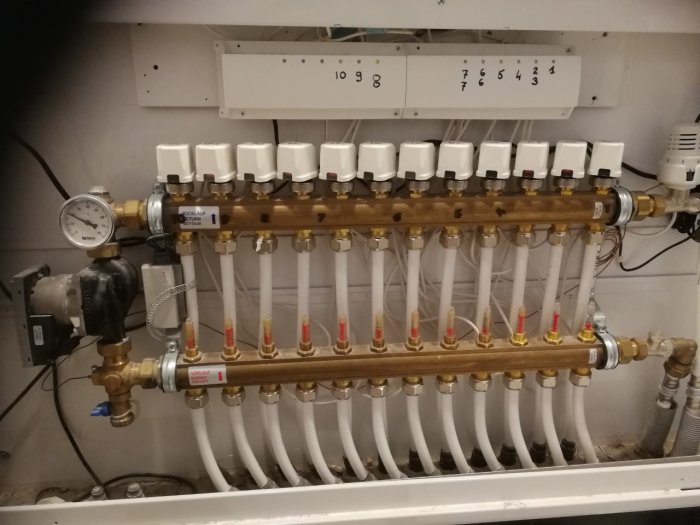 Golvvärmefördelare med termostatventiler och rörsystem i tekniskt utrymme.