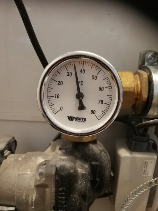 Mätare på ca 35 grader monterad på ett HVAC-system, med fokus på termometerns visare och skalan.