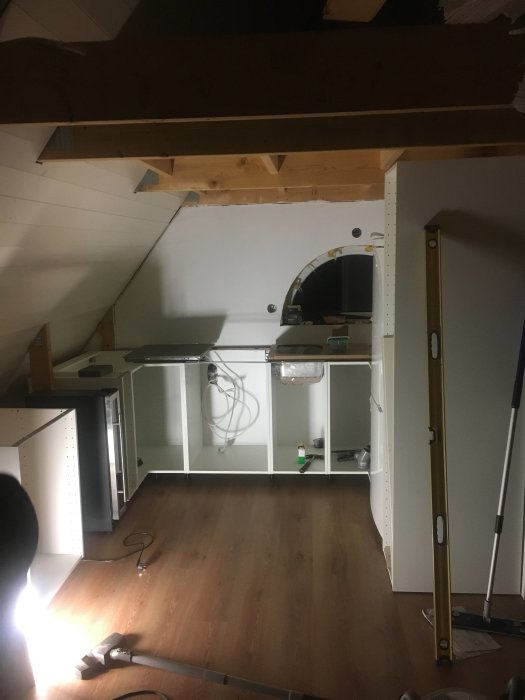 Köksmontering på loft med Ikea Bodbyn luckor, vita väggar och laminatgolv, omonterat kakel.