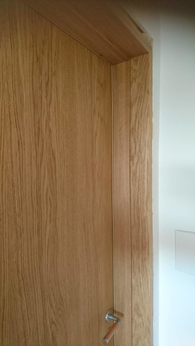 Nyinstallerad massiv ekdörr med tät drevning längs karmen, synlig tätningslist och stängd dörrhandtag.