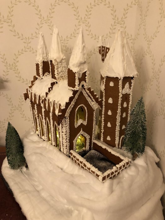 Hemmagjord pepparkakskreation av Hogwarts täckt av "snö" med kristyr, mot bakgrund av tapet.