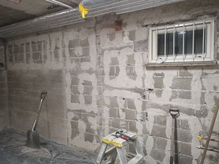 En källare under renovering med halvfärdiga Leca-blockväggar och installationsutrymme, samt arbetsredskap.