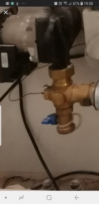 Närbild av en VVS-installation med en mässingsventil och ett kapillärrör som leder till en annan komponent.