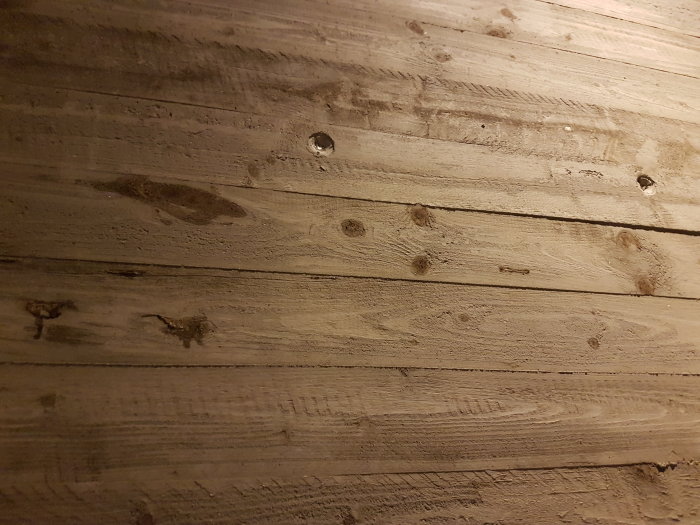 Betongvägg med detaljerad träplankstruktur och synliga knotthål, liknar en trävägg.