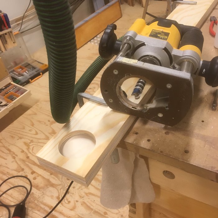 Trähantverk i verkstad med användning av handöverfräs för att forma hål i en träbit.